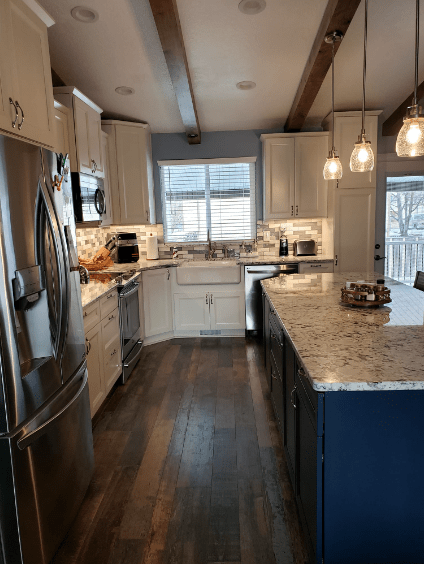 Modern kitchen with white cabinets, stainless steel appliances, and hanging lights